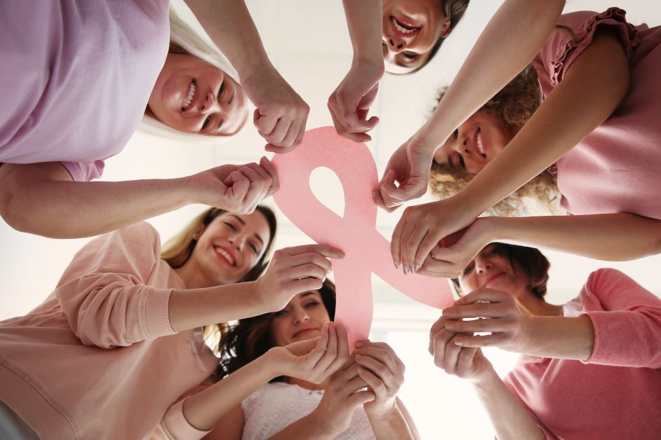 Women holding pink paper ribbon, bottom view. Breast cancer awareness concept